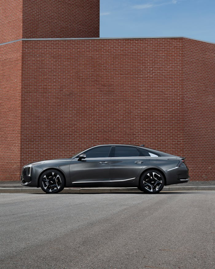 Modern grey sedan parked outdoors against a brick wall, showcasing its sleek design.